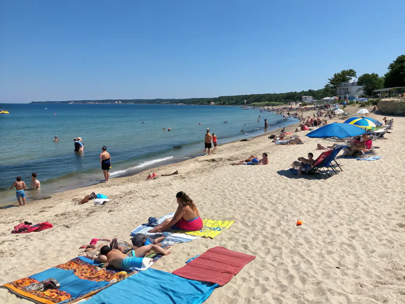 A group of people happily walking in shallow coastal water during a sunny day, showcasing the physical activity and enjoyment of coastal water walking.